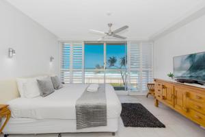 黄金海岸Golden Sands on the Beach - Absolute Beachfront Apartments的一间白色卧室,配有床和电视