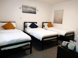 伦敦Wanstead Hotel的配有白色和橙色枕头的三张床