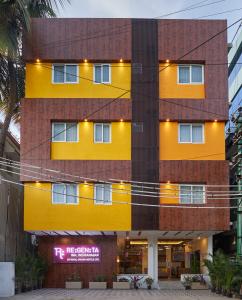 班加罗尔Regenta Inn Indiranagar by Royal Orchid Hotels的黄色的建筑,前面有标志