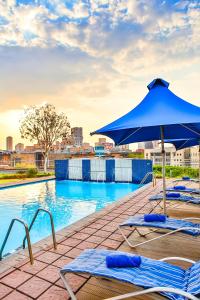 比勒陀利亚RH Hotel Pretoria的游泳池旁的游泳池配有蓝色遮阳伞和椅子
