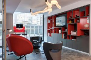 米兰iQ Hotel Milano的客厅配有红色和黑色的椅子和电视