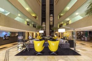巴西利亚巴西21美利亚酒店的大楼内带黄色椅子和桌子的大堂