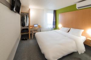 默兹河畔凡尔登B&B HOTEL Verdun的酒店客房设有一张白色大床和一张书桌