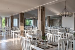 瓦西里亚斯Kassandra Bay Resort, Suites & Spa的用餐室配有白色的桌子和白色的椅子