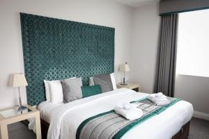 大莫尔文马尔文酒店的一间卧室配有一张大床和绿色床头板