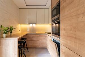 萨格勒布Anna的厨房配有木制橱柜和带凳子的台面