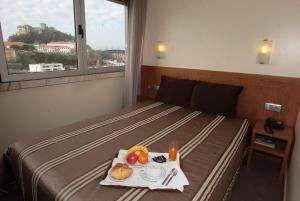 莱里亚圣弗朗西斯科酒店的一间酒店客房,配有一张床铺,上面放着一个食物托盘
