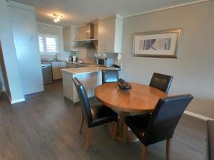 开普敦Lagoon Beach Hotel Apartments的厨房以及带木桌和椅子的用餐室。