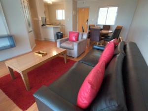 开普敦Lagoon Beach Hotel Apartments的客厅配有带红色枕头的黑色皮沙发