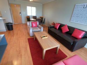 开普敦Lagoon Beach Hotel Apartments的客厅配有黑色沙发和红色枕头