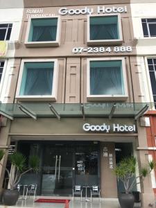 新山GOODY HOTEL的一座配有桌椅的建筑前的商店