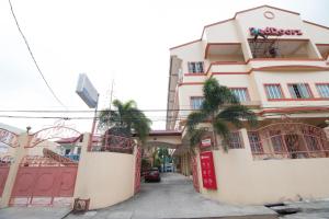 卡兰巴RedDoorz Praferosa Resort Hotel Calamba的前面有棕榈树的粉红色建筑