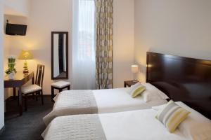 尼斯阿克罗波利斯驿站酒店的酒店客房设有两张床、一张桌子和一张书桌。
