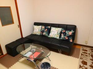 富士吉田市富士山結アパートメント的客厅里一张黑色的沙发,配有玻璃桌
