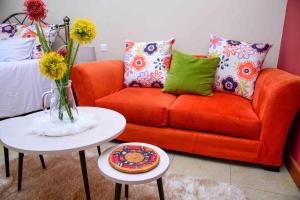 内罗毕West Suites Sherry Homes的客厅配有橙色沙发和桌子