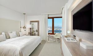 马略卡岛帕尔马Hotel Victoria Gran Meliá的白色卧室设有一张大床和一台平面电视。