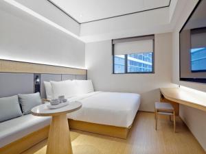 新加坡Ji Hotel Orchard Singapore的一间卧室配有一张床、一张桌子和一台电视。