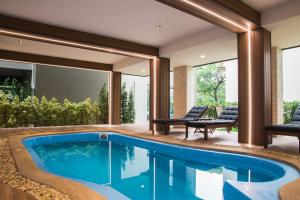 曼谷B Stay Hotel - SHA Plus Certified的一座配有两把椅子和一张桌子的房子内的无边泳池
