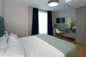 萨兰达Buzë Boutique Hotel的卧室配有一张白色大床和一张书桌