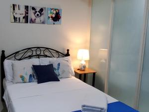 马尼拉Jen's Paranaque City Apartment的一间卧室配有一张床和一张桌子上的台灯