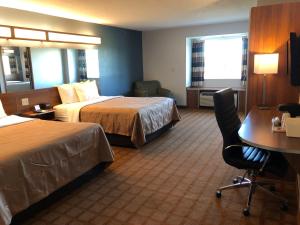 CalciumQuality Inn & Suites Watertown Fort Drum的酒店客房配有两张床和一张书桌