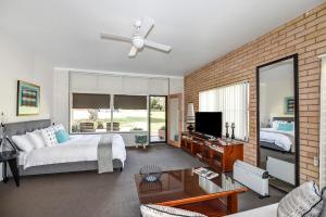 麦夸里港Fi's Beach House的一间卧室设有床铺、电视和砖墙