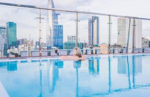 胡志明市Happy Life Grand Hotel & Sky Bar的坐在游泳池里俯瞰城市的女人