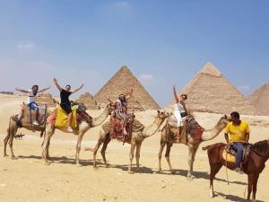开罗Queen Pyramids View Inn的一群人骑着骆驼,在金字塔前骑