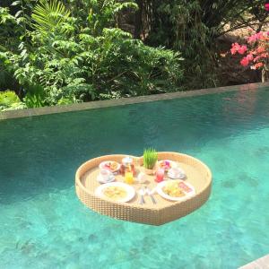 乌布Gek House Ubud Bali的游泳池里的餐桌上放着食物