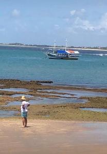 普拉亚多village na praia do forte的水中乘船在海滩上行走的人