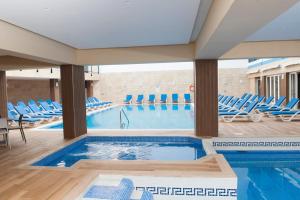 圣保罗湾城欧罗俱乐部酒店的一个带蓝色椅子的游泳池和一个游泳池