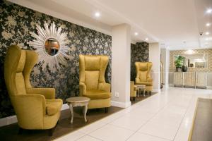 比勒陀利亚Hotel 224 & Apartments的一间设有黄色椅子和镜子的等候室