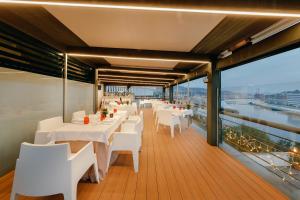 毕尔巴鄂Abba Euskalduna Hotel的阳台餐厅设有白色桌子和白色椅子