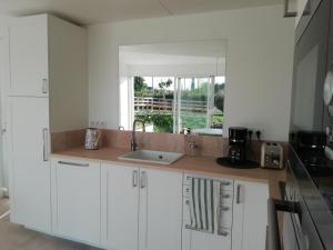 PlurienEsprit Cottage "4 étoiles" sables d'Or les pins的厨房配有白色橱柜、水槽和窗户。