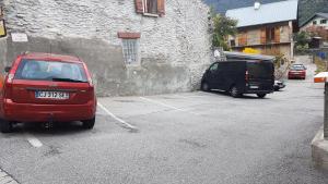 布拉芒Gites de la combe的两辆汽车停在大楼旁边的停车场