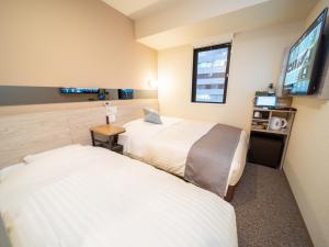 东京Super Hotel Premier Akihabara的酒店客房设有两张床和一台平面电视。