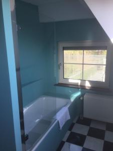 布雷达B&B de Druif的蓝色的浴室设有浴缸和窗户。