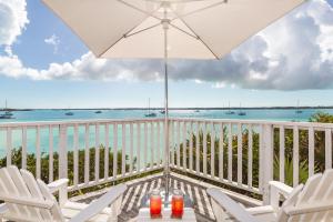 乔治镇Peace and Plenty Resort的一个带椅子和遮阳伞的阳台,并享有海景。