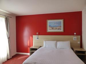 罗瑟勒姆迎宾罗瑟勒姆/谢菲尔德酒店的卧室设有红色的墙壁和一张床