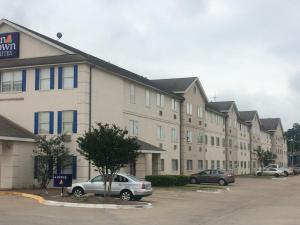 休斯顿InTown Suites Extended Stay Select Houston TX - BrookHollow的大型公寓大楼,停车场有车辆停放