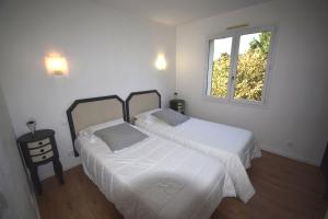洛特河畔的维伦纽夫VILLA PECH DE DURAND VILLENEUVE SUR LOT的白色客房的两张床,设有窗户