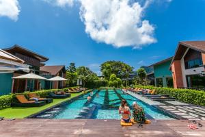 皮皮岛ChaoKoh Phi Phi Hotel and Resort- SHA Extra Plus的度假村的游泳池,人们坐在躺椅上