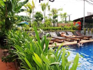 暹粒Jasmine Lodge Siem Reap的度假村内带躺椅和桌子的游泳池