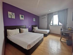 古晋帕顿甘酒店的一间卧室设有一张大床和紫色的墙壁