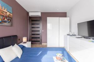 SafiBelvedere Airport Suites的一间卧室配有蓝色的床和电视