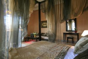 马拉喀什阿尔法希亚阿古达尔酒店的一间卧室配有一张天蓬床和一张桌子