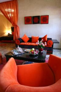 马拉喀什阿尔法希亚阿古达尔酒店的客厅配有橙色沙发和桌子