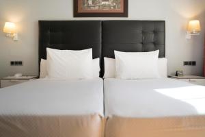 维戈三盏灯斯考特而酒店的配有白色枕头的酒店客房内的两张床