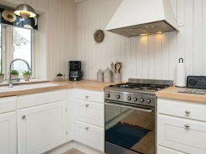 桑德比耶特6 person holiday home in Bjert的厨房配有白色橱柜和炉灶烤箱。