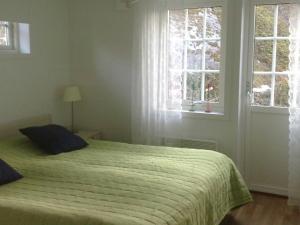 Arkösund维克博兰德两卧室度假屋 的一间卧室配有一张带绿色棉被的床和两个窗户。
